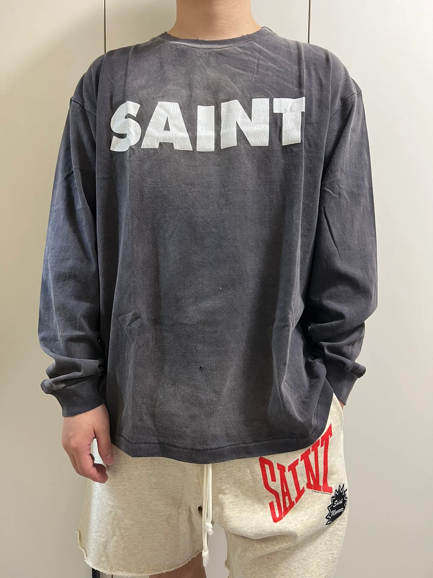 SAINT Mxxxxxx S>N>T LS TEE/BLACK Autumn and winter new style S>N>T slogan crack printed long TEE, washed black S-XL Asut ready-made garments dyed, the whole piece sprayed with horse-hair spray, and then sprayed again to fade the color. The collar and cuffs are frayed. Many hangings are worn NEW VINTAGE. Heavy craftsmanship.